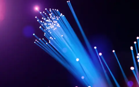 Leuchtende Glasfaserkabel in Blau und Lila. Die Frage "wie viel mbits sind gut wlan" wird durch die Darstellung von Highspeed-Datenübertragung visuell beantwortet.