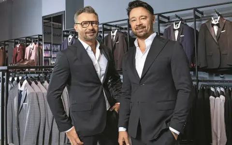 Dwóch eleganckich mężczyzn w garniturach, w sklepie z odzieżą męską. Czy to Pako Lorente czy Vistula?