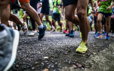 Läufer auf einer Strecke, die die halbmarathon distanz bewältigen. Fokus auf die Beine und Laufschuhe.