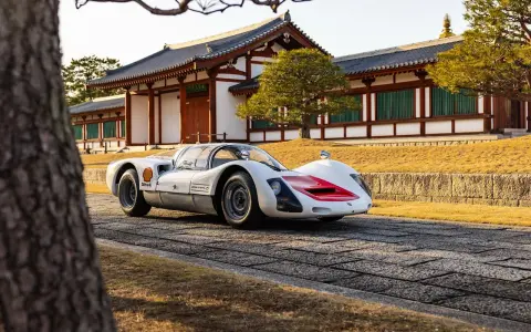 Ein weißer Porsche 966 mit roten Akzenten steht vor einem traditionellen japanischen Gebäude.