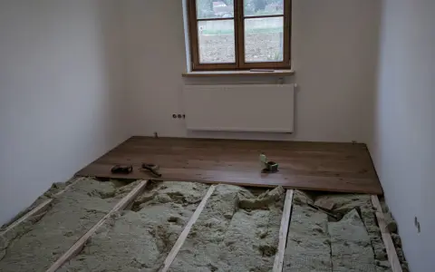 Podłoga na legarach na poddaszu, w trakcie montażu drewnianych desek. Widoczna wełna mineralna izolacyjna.
