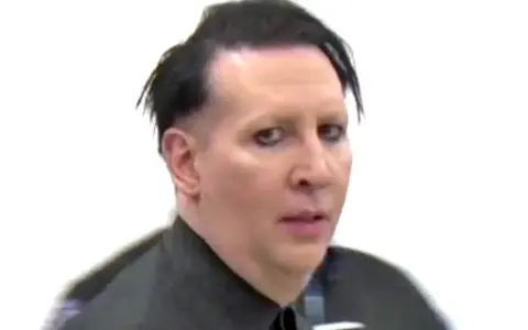Marilyn Manson bez makijażu, z charakterystycznym makijażem oczu, w czarnej koszuli.