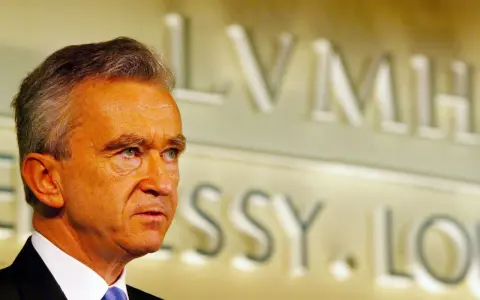 Bernard Arnault, proprietario Dior, guarda pensieroso. Sullo sfondo, il logo LVMH.