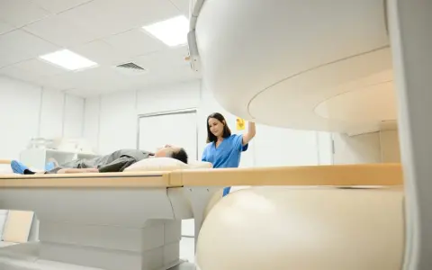 Pacjent leży na stole do rezonansu magnetycznego, pielęgniarka przygotowuje badanie. Rezonans barku interpretacja jest kluczowa dla diagnozy.