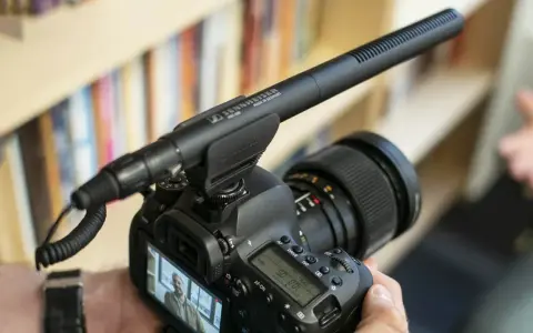 Kamera z mikrofonem kierunkowym Sennheiser MKE 600 na gorącej stopce. Tło to półka z książkami.