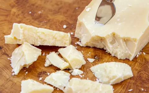 Kawałki parmezanu, znanego też jako Grana Padano, na drewnianej desce.