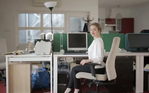 Uśmiechnięta sekretarka przy biurku w szkole. Zastanawiasz się, ile zarabia sekretarka w szkole?