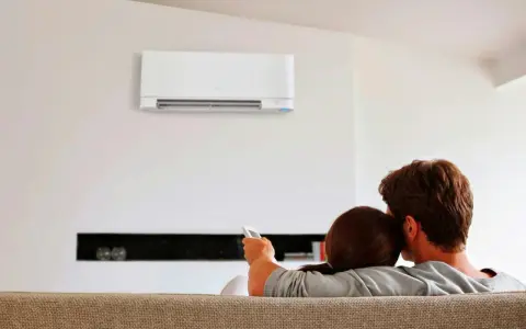 Pareja relajada en el sofá, disfrutando del confort que ofrece un **split aire acondicionado** en la pared.