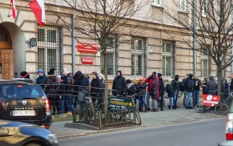 Kolejka do odbioru paszportu w Krakowie. Ludzie stoją przed budynkiem urzędu.