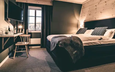 Mysigt rum på vandrarhem i Åre med stor säng, TV och fönster med utsikt.