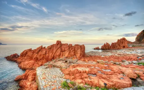 Scogliere rosse e sentiero in pietra a picco sul mare. Un luogo suggestivo da scoprire: Arbatax cosa vedere.
