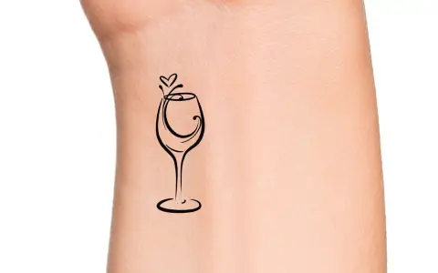 Delikatny tatuaż kieliszek wina z serduszkiem nad nim, symbolizujący miłość do wina i chwil relaksu.