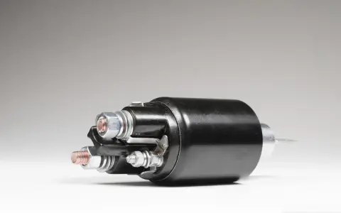 A black starter solenoid with copper and silver bolts, ready to power up an engine.