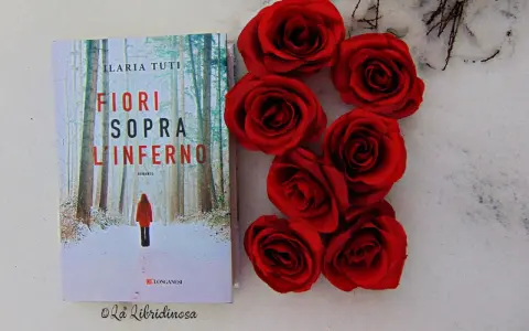 Copertina del libro "Fiori sopra l'inferno" di Ilaria Tuti, con rose rosse su sfondo innevato.