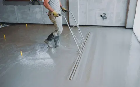 Budowlaniec wyrównuje świeży **miksokret** za pomocą specjalnego narzędzia.