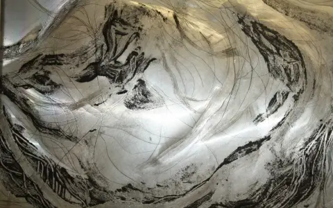 Textura metálica con trazos negros y finas líneas, evocando un grabado en carborundum.