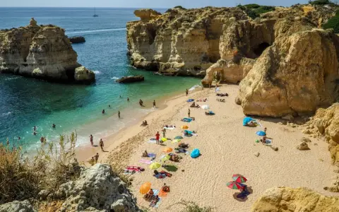 Słoneczna plaża w Algarve, z turkusową wodą i skalnymi klifami. Idealne miejsce, by zobaczyć piękno Portugalii.