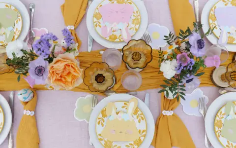 Jolie table de Pâques avec des lapins en papier, des fleurs fraîches et des œufs décorés. Une belle idée déco table Pâques pour un repas printanier.