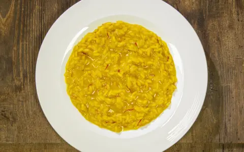 Un cremoso risotto alla milanese, con i suoi fili rossi di zafferano che promettono un sapore autentico.