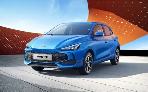 Niebieski samochód MG3 Hybrid+ na tle nowoczesnej architektury.