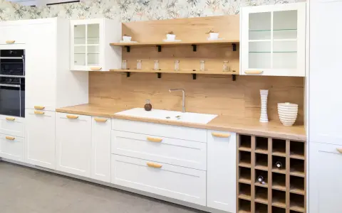 Cocina moderna blanca con encimera de madera, estantes flotantes y botellero. Inspiración para tus ideas de cocinas.