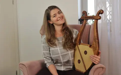 Uśmiechnięta kobieta trzyma instrument muzyczny, który wygląda jak skorupa żółwia.