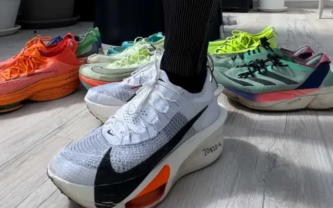 En person visar upp sina löparskor, redo för hoka halvmaraton. Flera färgglada skor ligger utspridda på golvet.