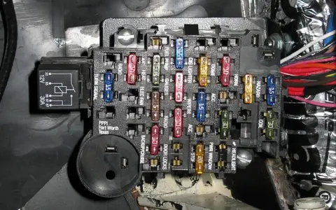 Caja de fusibles de coche con varios fusibles de colores y etiquetas. Aprende cómo quitar un fusible del coche para reparaciones.