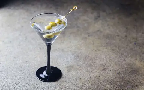 Klasyczny Dirty Martini przepis: schłodzony gin, wermut i oliwki na wykałaczce w eleganckim kieliszku.