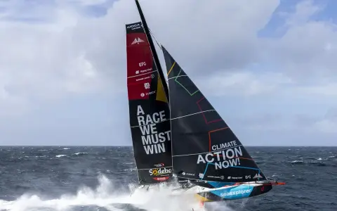 Segelboot mit der Aufschrift "A RACE WE MUST WIN" und "CLIMATE ACTION NOW!" auf dem Weg zum Vendée Globe.