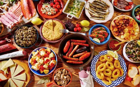 Tapas co to? Kolorowy stół pełen hiszpańskich przekąsek: kiełbaski, krewetki, owoce morza, tortilla, sery i wędliny. Prawdziwa uczta!