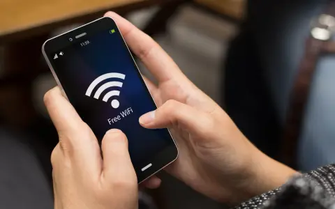 Dłonie trzymają smartfon z ikoną Wi-Fi i napisem "Free WiFi". Zastanawiasz się, co pobiera najwięcej internetu w telefonie?