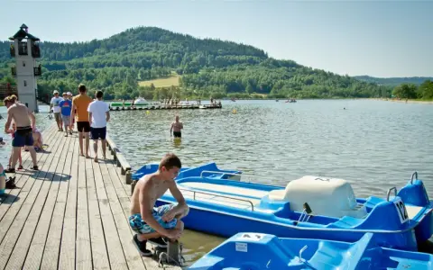 Letni dzień nad jeziorem, popularne wśród turystów śląskie atrakcje turystyczne. Ludzie odpoczywają na pomoście i w wodzie.