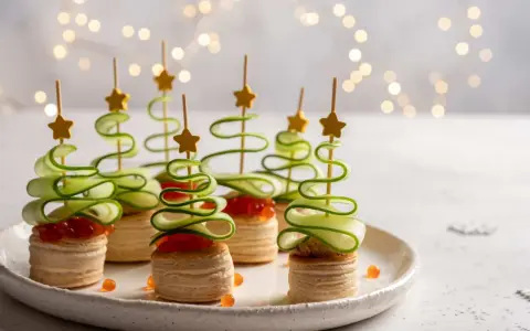 Aperitivos navideños en forma de árbol con pepino en espiral y estrellas doradas.