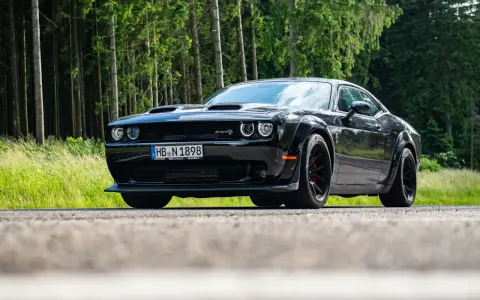 Schwarzer Dodge Challenger SRT Hellcat Redeye parkt am Waldrand.