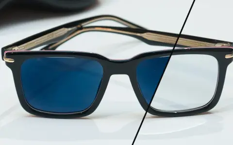 Eleganckie okulary z czarnymi oprawkami, po lewej stronie ciemne szkła fotochromowe, po prawej jasne.