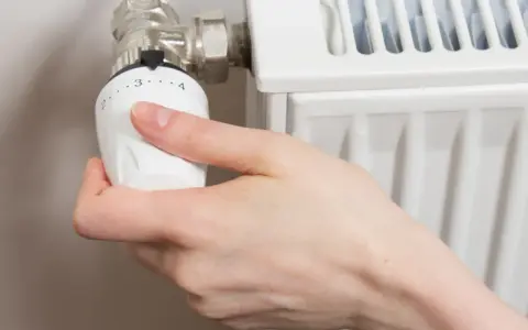 Mano ajustando el termostato para abrir radiador derecha o izquierda.