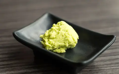 Zielona pasta, czyli co to jest wasabi, na czarnej, kwadratowej miseczce.