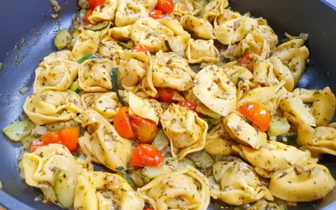 Pyszne danie z tortellini na obiad, z pomidorkami koktajlowymi i cukinią, doprawione ziołami.
