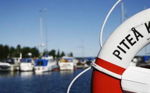 Livboj med texten PITEÅ K visar en hamn med båtar. Ett perfekt ställe att besöka Piteå på!