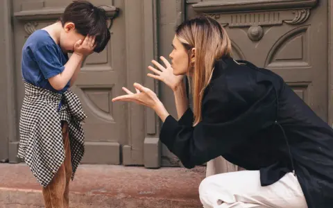 Madre explica a su hijo cómo poner límites a los niños. El niño se tapa la cara con las manos, visiblemente afectado.