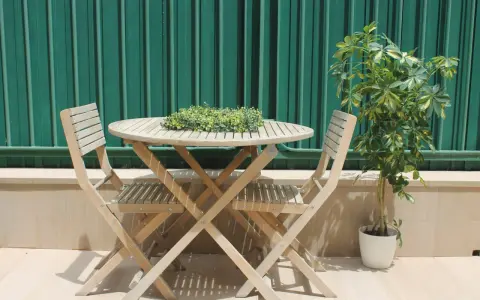 Conjunto de madera para dos personas en unas terrazas pequeñas con encanto. Una planta verde decora el rincón.