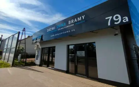 Nowoczesny salon z oknami i drzwiami, z szyldem "DRZWI OKNA BRAMY" i numerem 79a.