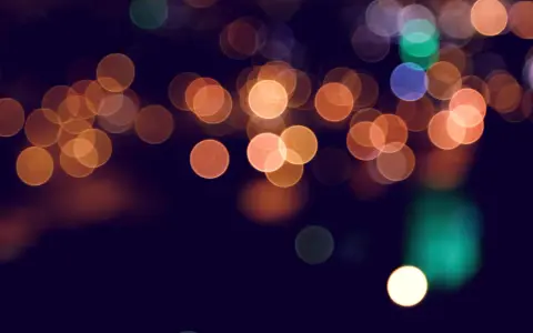 Rozmyte, okrągłe światła tworzą magiczny **bokeh** na ciemnym tle.