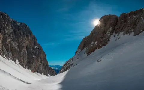 Sole che filtra tra le vette innevate, un invito a scoprire cosa vedere in Friuli Venezia Giulia, tra sentieri e panorami mozzafiato.
