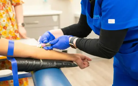 Pielęgniarka w niebieskim uniformie podczas kursu medycyny pracy pobiera krew.