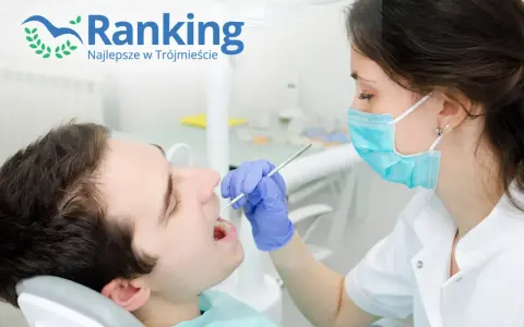 Dentystka w masce bada zęby pacjenta w gabinecie stomatologicznym.