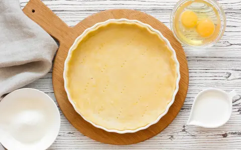 Préparation d'une pâte sucrée pour une tarte. Ingrédients : pâte dans un moule, œufs, sucre, lait.