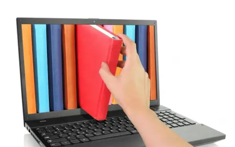 Mano saca un libro rojo de una estantería digital en una laptop. Acceso a información y al libro de IVA.