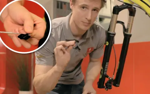 Man visar hur man byta bromsklossar på en cykel. En närbild visar en liten svart bromskloss.